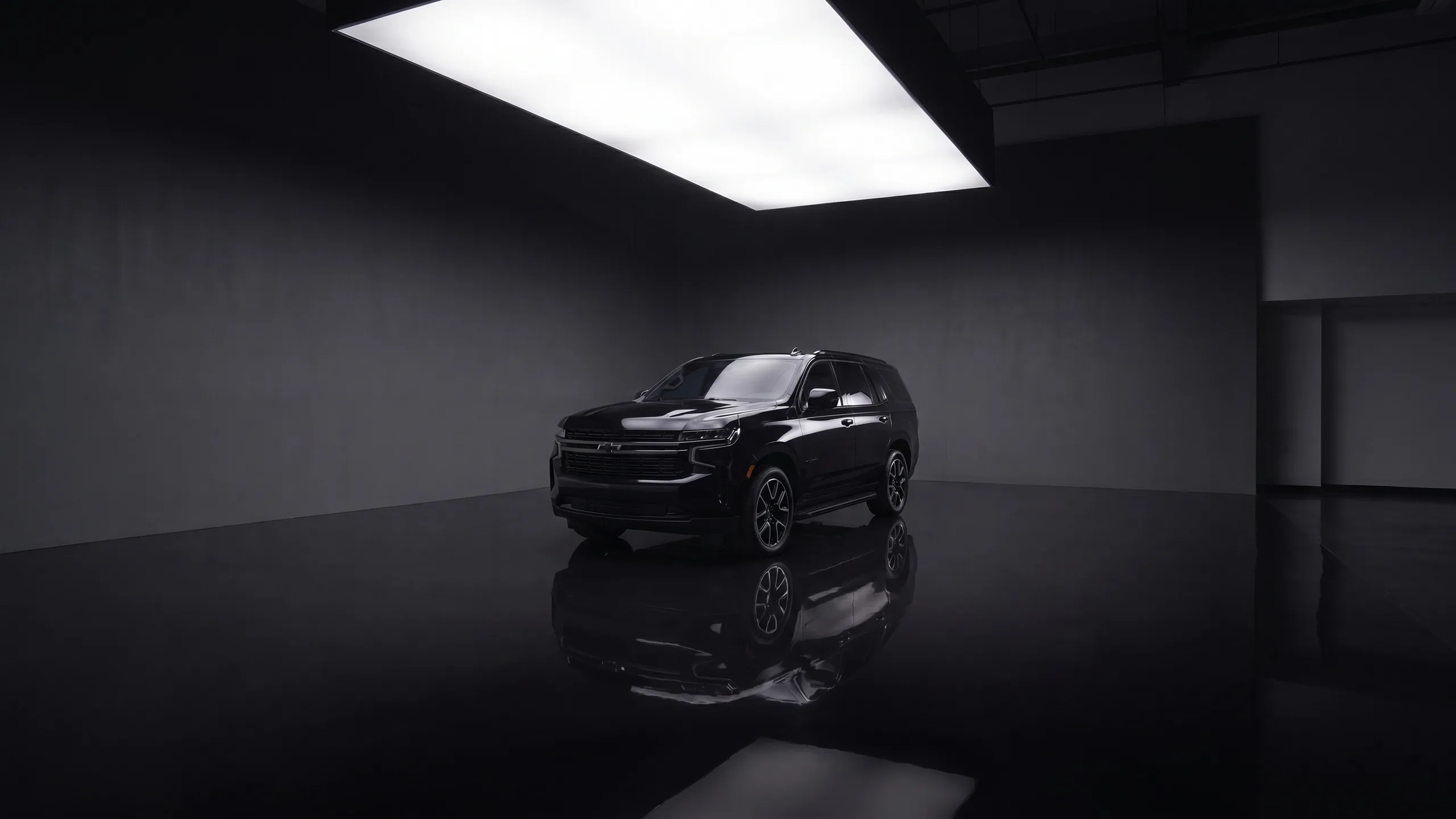 Black Chevrolet Tahoe in the Seven Star showroom, lightbox overhead and mirror reflection below — the group and black-truck chauffeur SUV for Vancouver airport runs and Whistler ski transfers