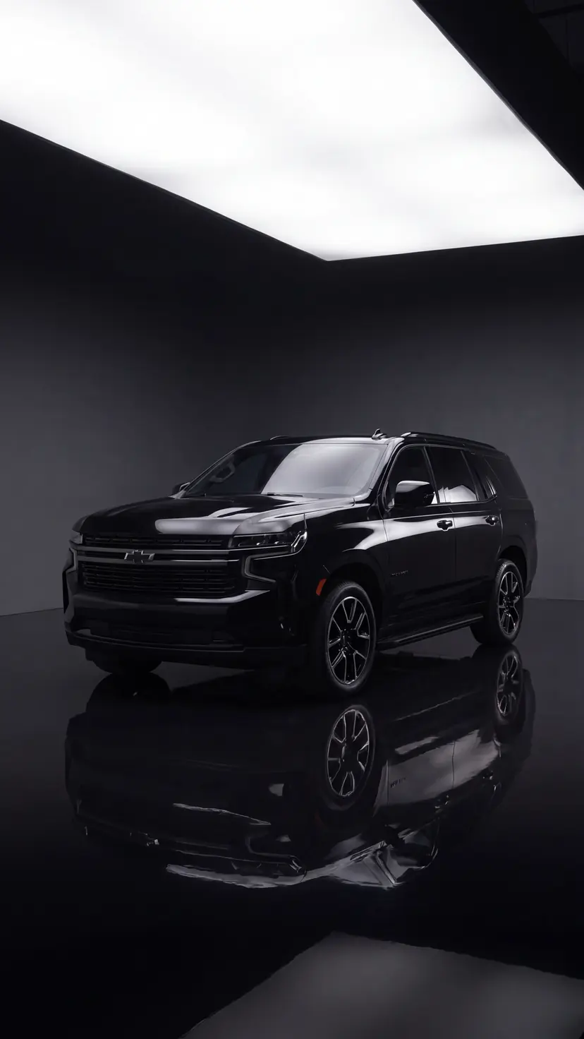 Black Chevrolet Tahoe in the Seven Star showroom, lightbox overhead and mirror reflection below — the group and black-truck chauffeur SUV for Vancouver airport runs and Whistler ski transfers